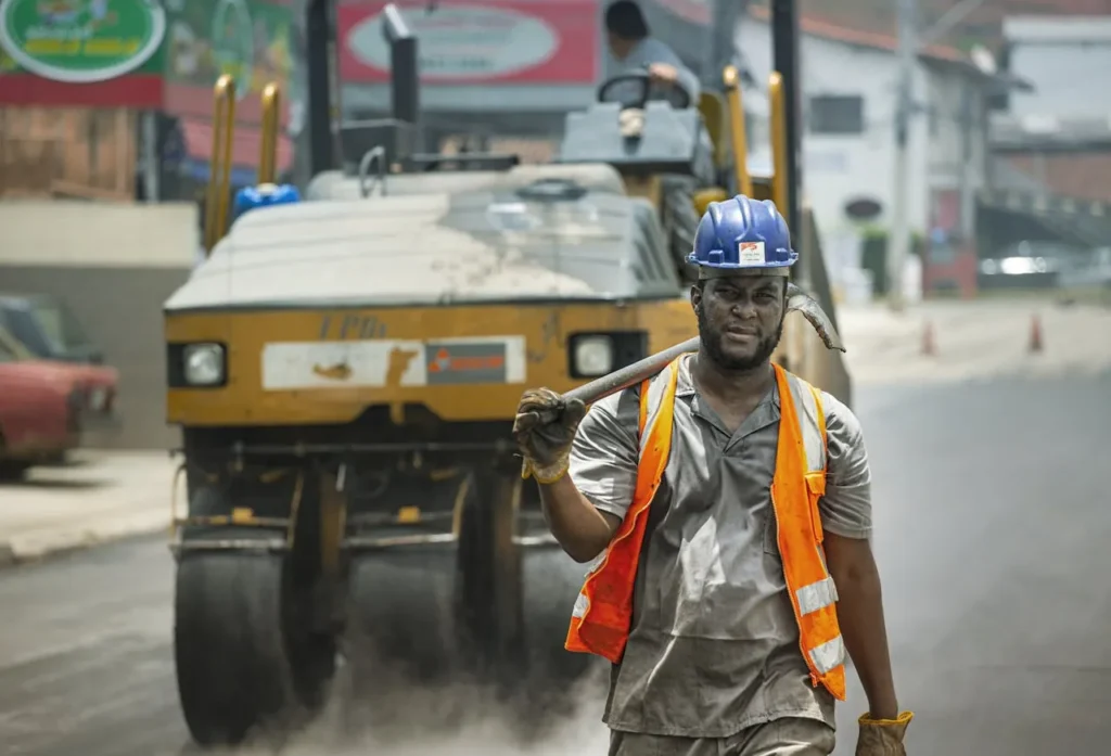 Road worker in safety gear working on street in Cotia, Brazil. A scene depicting urban construction activity.